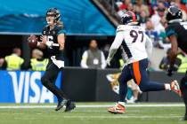 Jacksonville Jaguars quarterback Trevor Lawrence (16) scrambles while Denver Broncos defensive ...