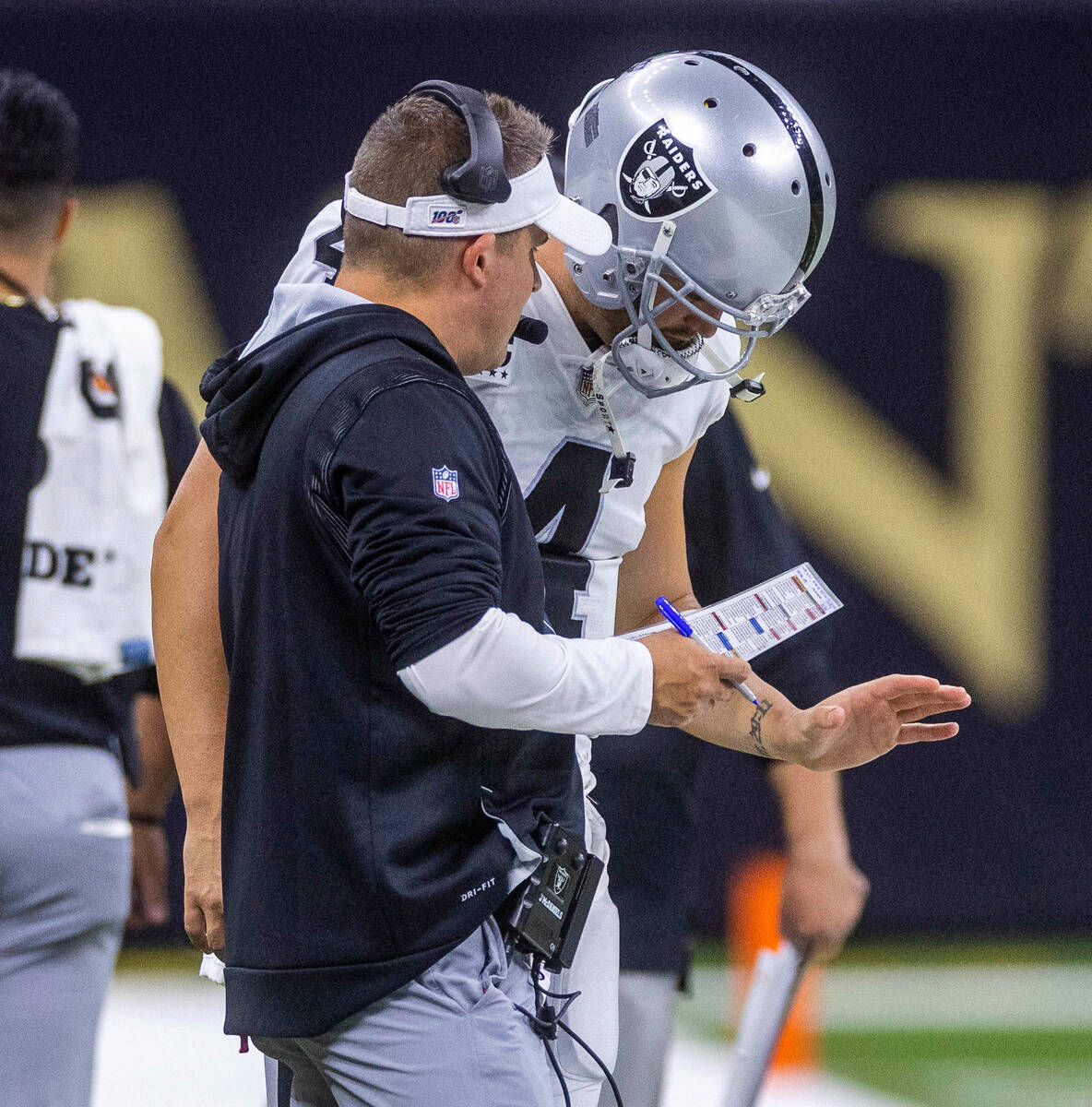 Raiders Head Coach Josh McDaniels confers on the sidelines with quarterback Derek Carr (4) vers ...