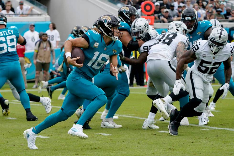 Jacksonville Jaguars quarterback Trevor Lawrence (16) carries the ball against the Las Vegas Ra ...