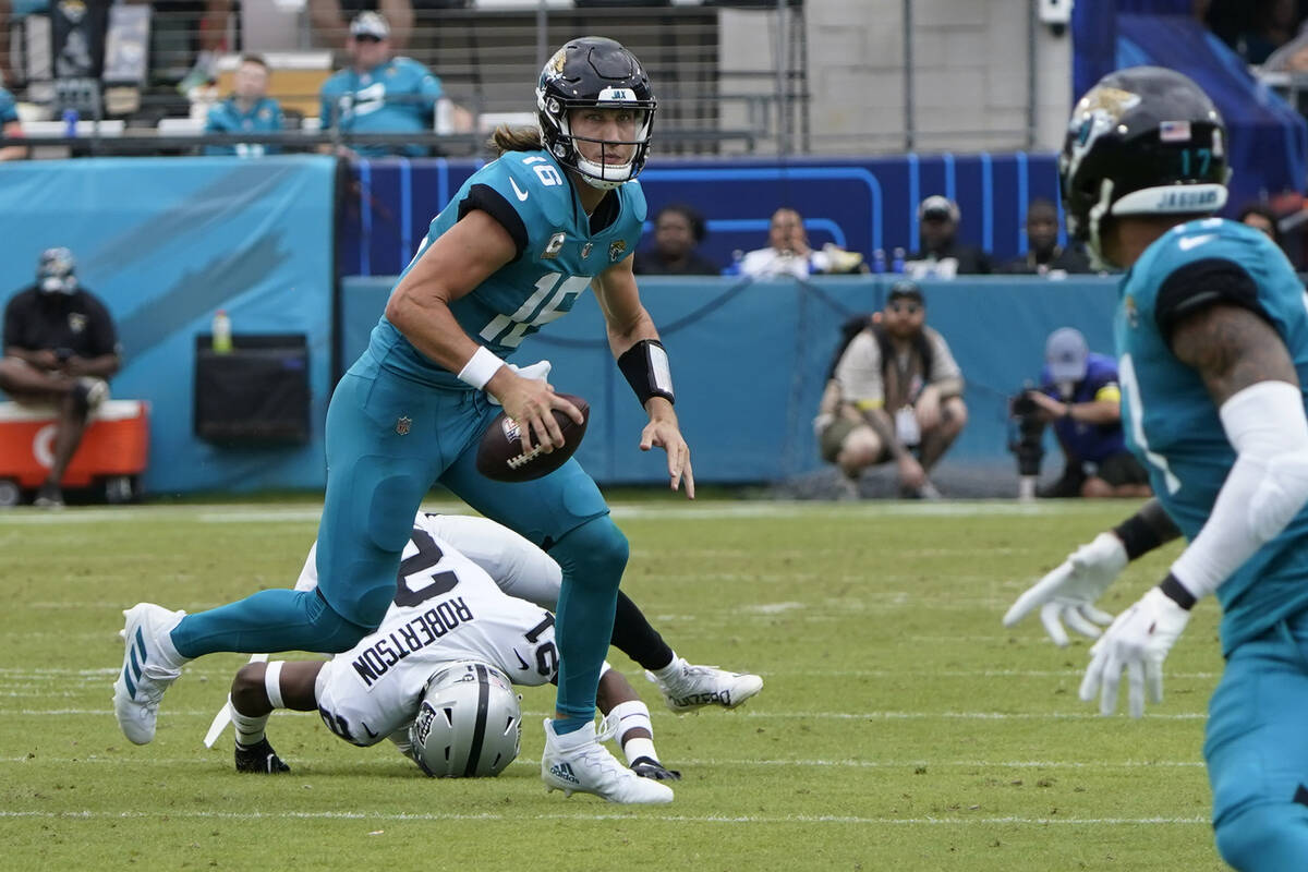 Jacksonville Jaguars quarterback Trevor Lawrence (16) scrambles away from Las Vegas Raiders cor ...