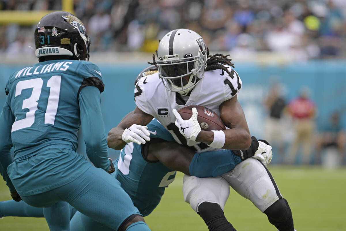 Las Vegas Raiders wide receiver Davante Adams (17) is stopped by Jacksonville Jaguars defenders ...