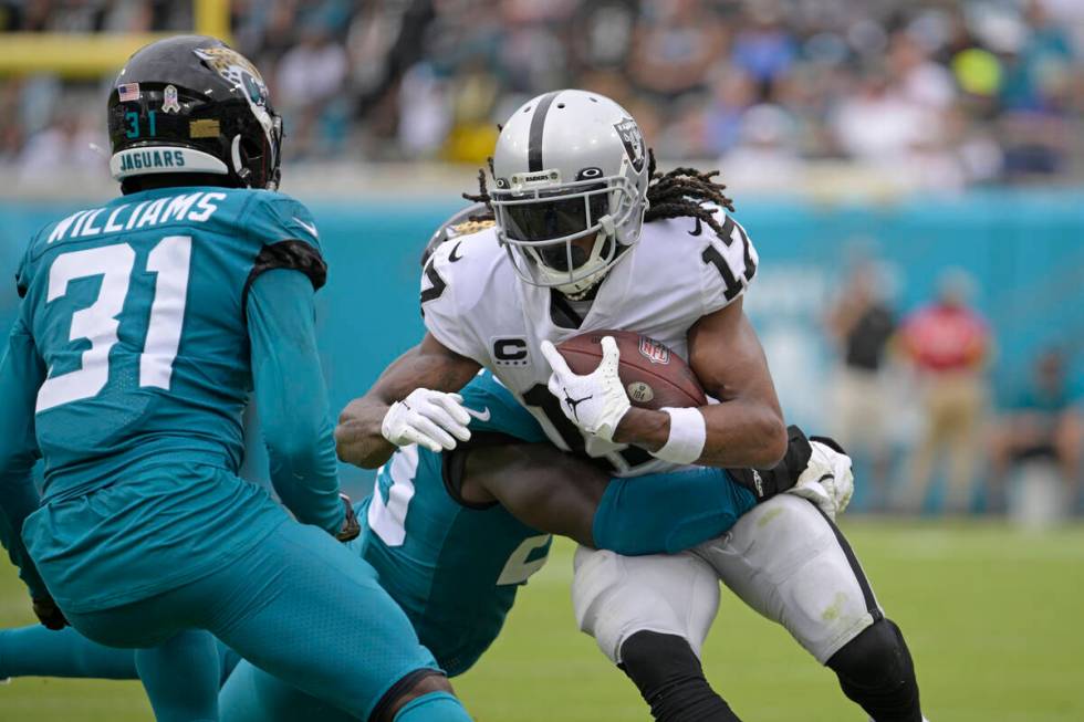 Las Vegas Raiders wide receiver Davante Adams (17) is stopped by Jacksonville Jaguars defenders ...