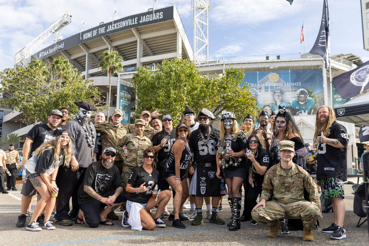 Raiders fans pose in front of TIAA Bank Field before an NFL game between the Raiders and the Ja ...
