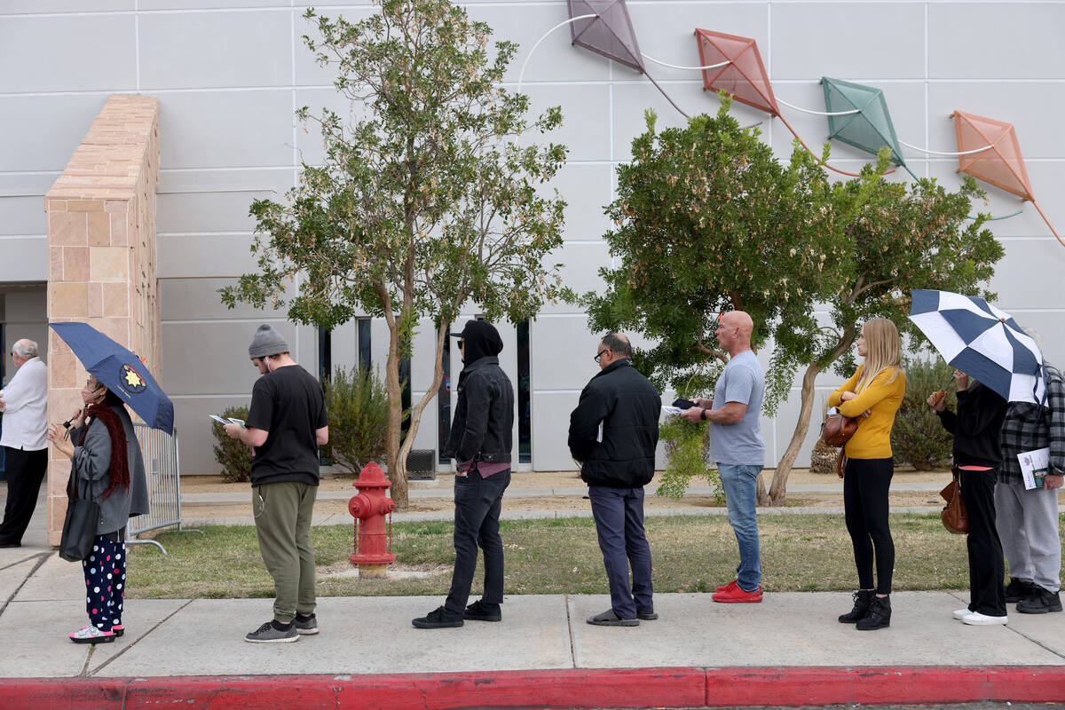 Voters brave high winds and rain drops while waiting in line on Election Day at Desert Breeze C ...