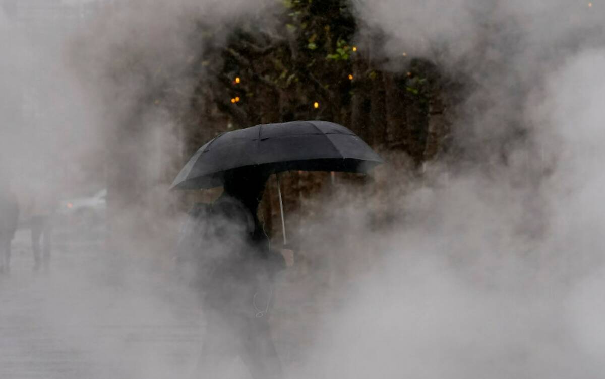 A pedestrian carries an umbrella while walking at Civic Center Plaza in San Francisco, Tuesday, ...