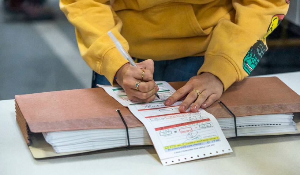 A worker signs an account form as they continue sorting ballots for final tabulations at the Cl ...
