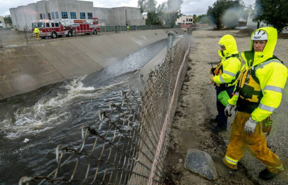 Firefighters look for people trapped in the rain-swollen Cucamonga wash in Ontario, Calif., on ...