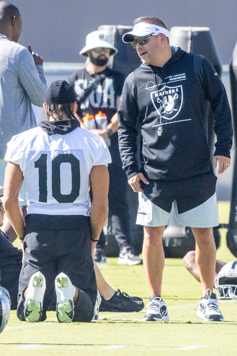 Raiders head coach Josh McDaniels meets with wide receiver Mack Hollins (10) during practice at ...