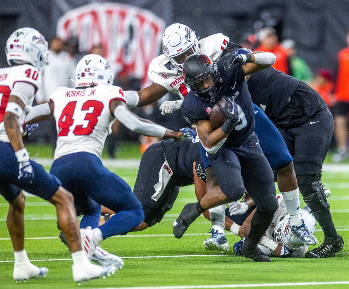 UNLV Rebels running back Aidan Robbins (9) looks to evade a tackle attempt by Fresno State Bull ...
