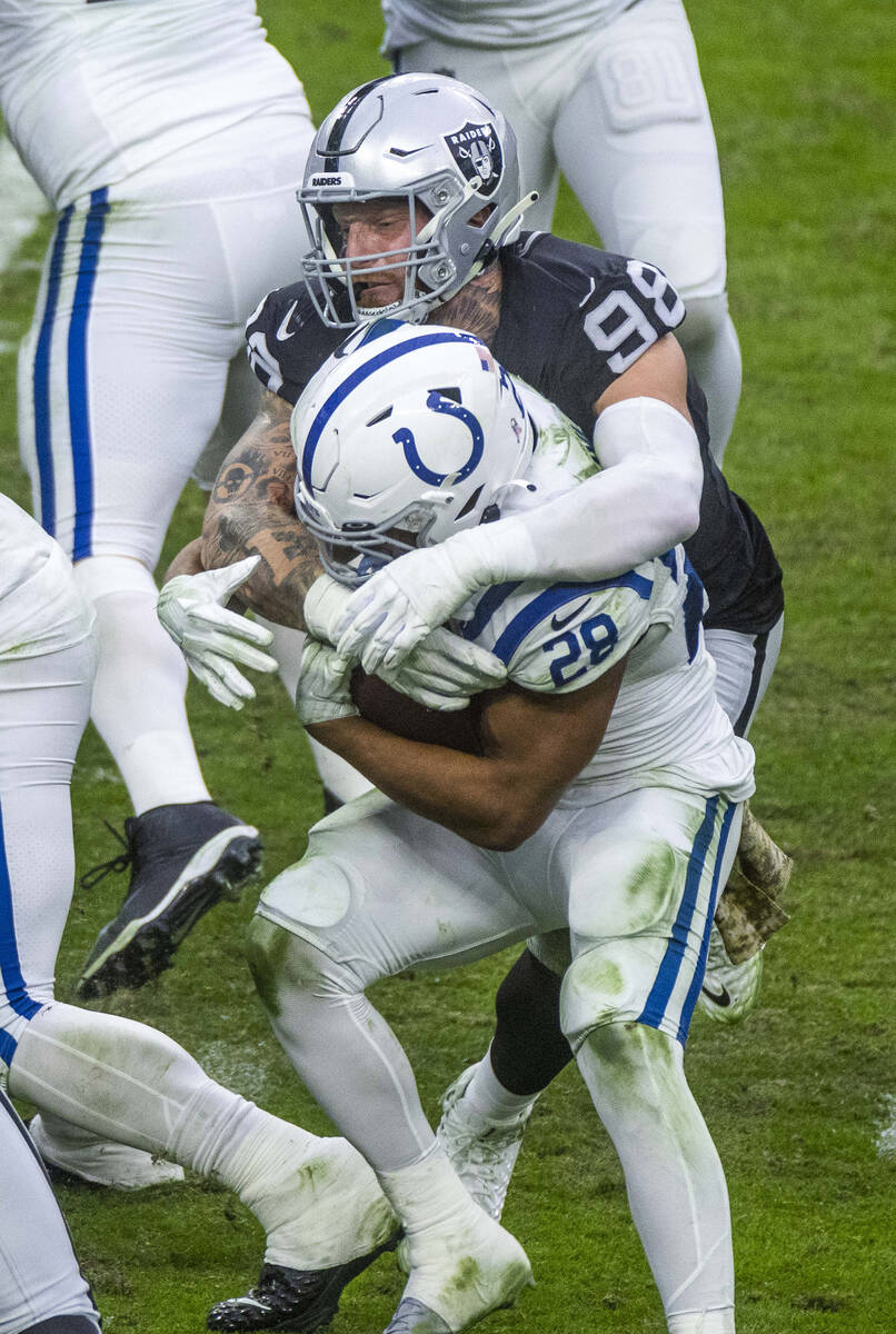 Raiders defensive end Maxx Crosby (98) wraps up Indianapolis Colts running back Jonathan Taylor ...