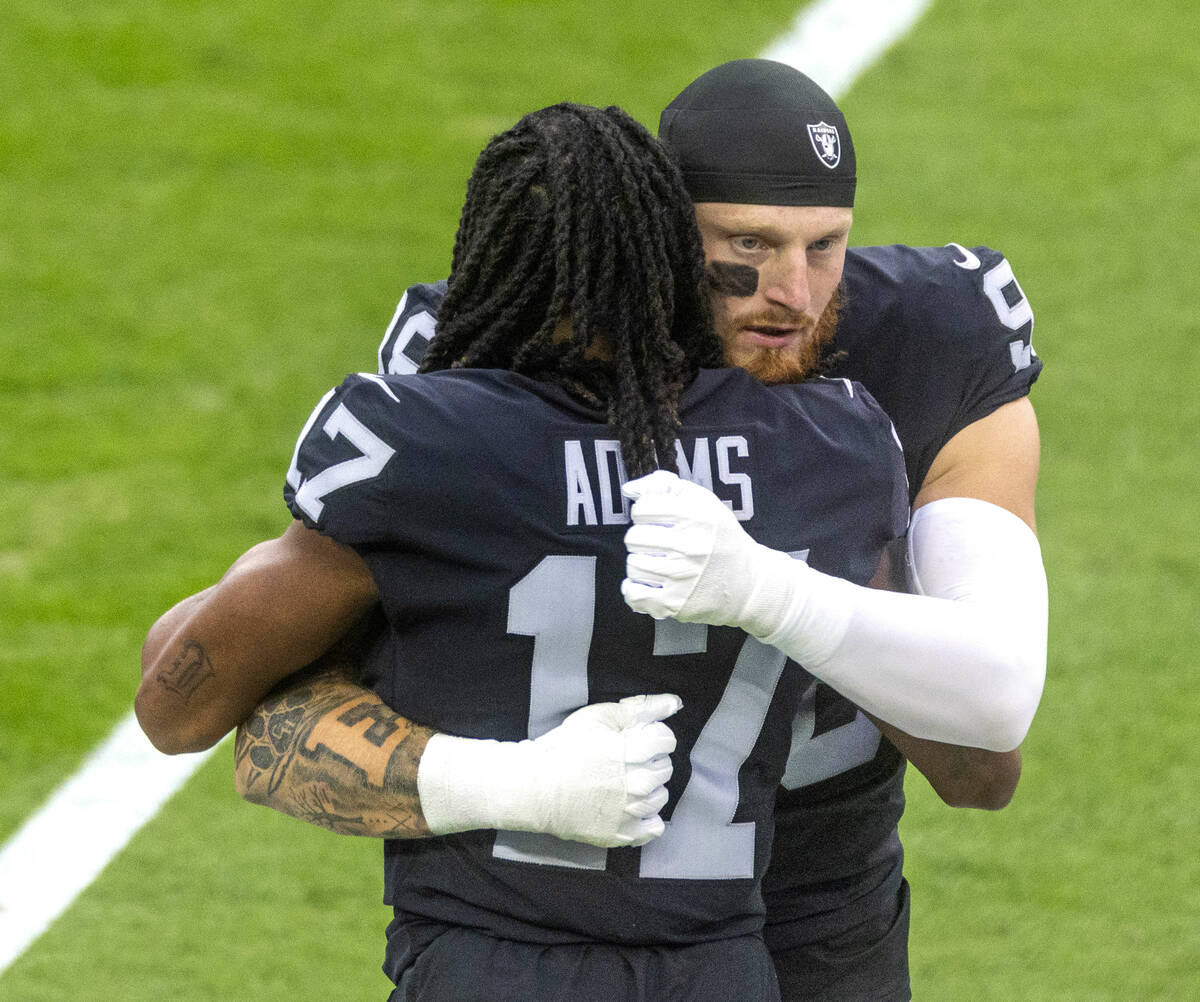 Raiders wide receiver Davante Adams (17) and Raiders defensive end Maxx Crosby (98) embrace on ...