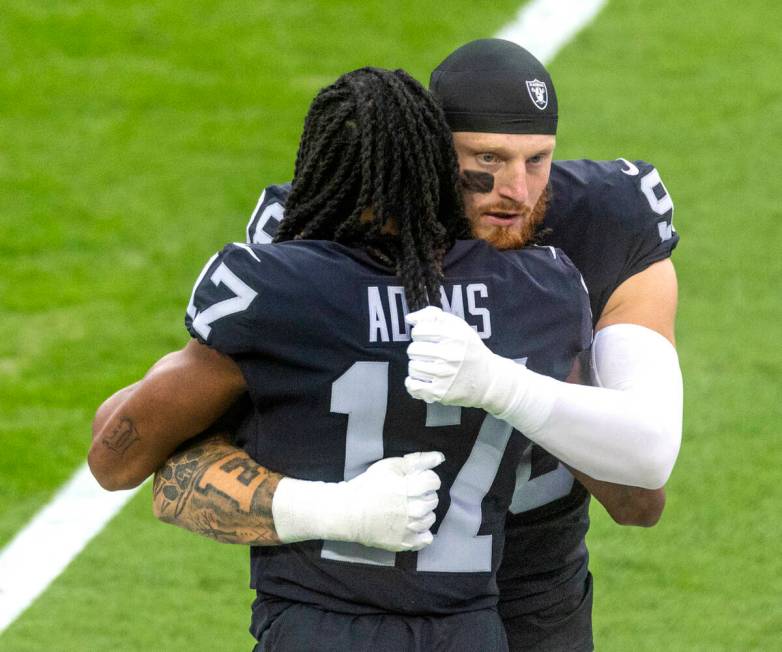 Raiders wide receiver Davante Adams (17) and Raiders defensive end Maxx Crosby (98) embrace on ...