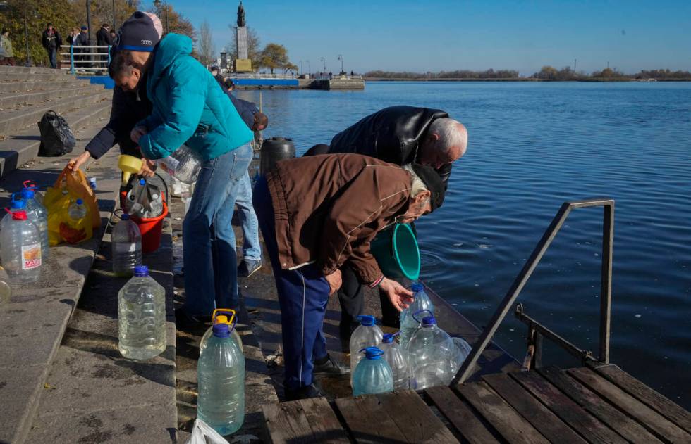 People collect water from a Dnipro river in Kherson, Ukraine, Tuesday, Nov. 15, 2022. Waves of ...