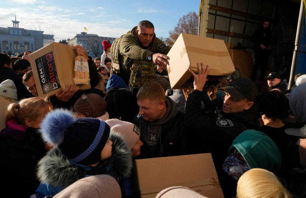 People receive humanitarian aid on central square in Kherson, Ukraine, Tuesday, Nov. 15, 2022. ...