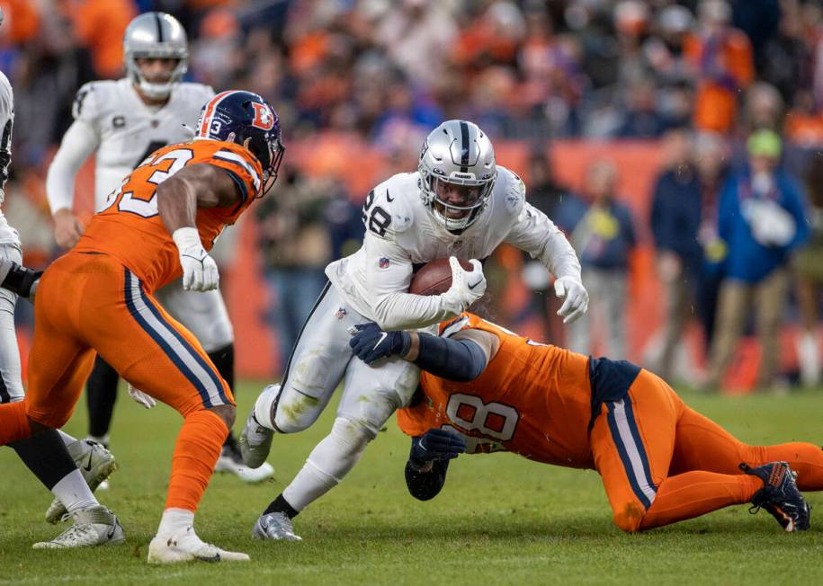 Raiders running back Josh Jacobs (28) looks for room to run against Denver Broncos defensive ta ...