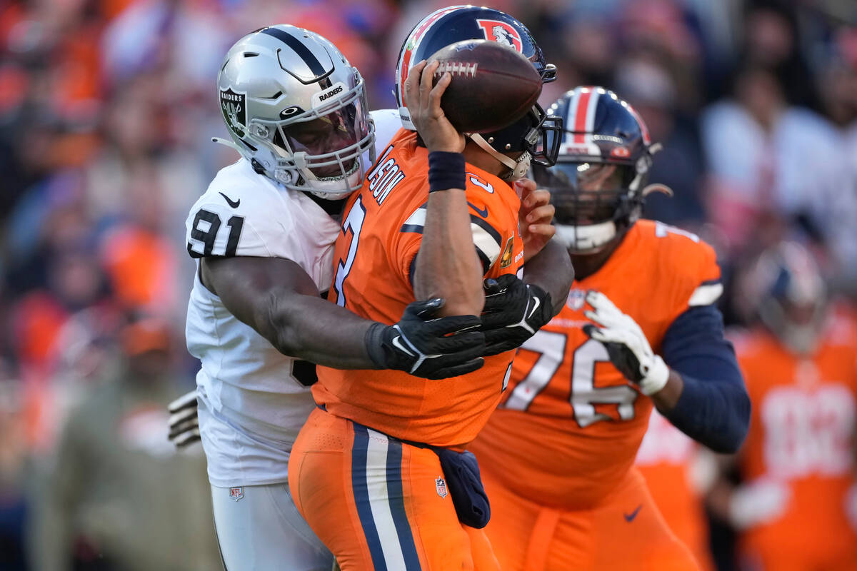 Denver Broncos quarterback Russell Wilson, middle, is hit by Las Vegas Raiders defensive tackle ...