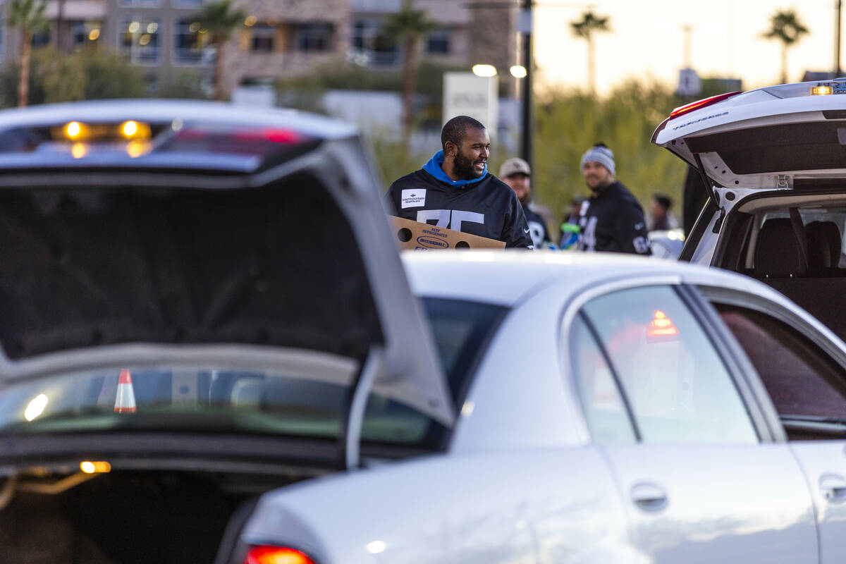 Raiders offensive tackle Brandon Parker (75) delivers turkeys as Raiders' current and former pl ...