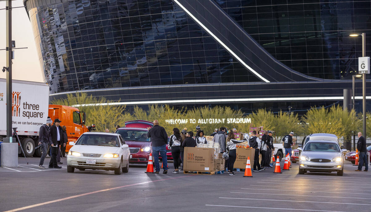 Cars weave their way around Allegiant Stadium as Raiders' current and former players along with ...