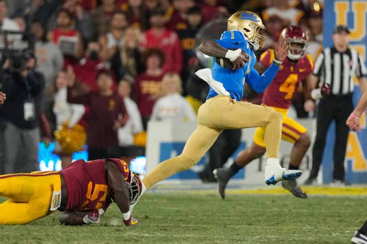 UCLA quarterback Dorian Thompson-Robinson, right, escapes a tackle by Southern California lineb ...