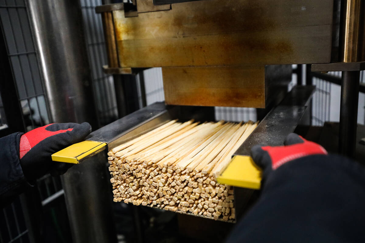 Production supervisor Nico Fenske places a batch of chopsticks in a device to be compressed at ...