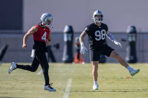 Raiders quarterback Derek Carr (4) and defensive end Maxx Crosby (98) warm up during practice a ...