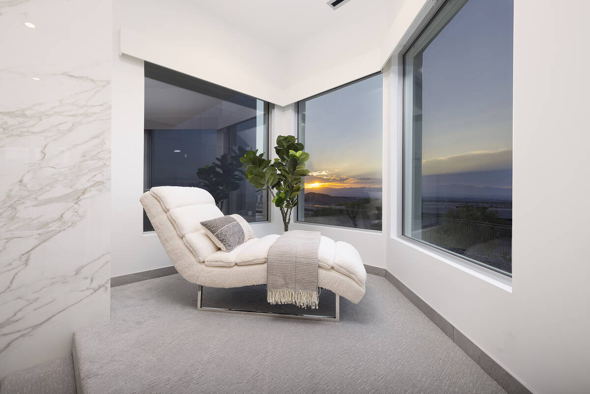 The master bedroom features an elevated seating nook and walls of glass showcasing stunning vie ...