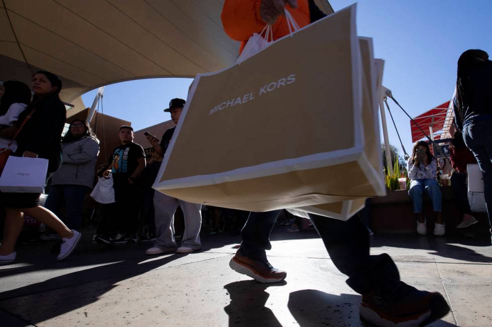 A shopper carries purchases from Michael Kors during Black Friday sales at Las Vegas North Prem ...
