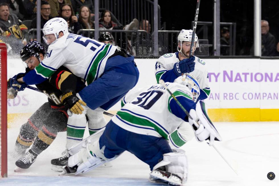 Golden Knights left wing William Carrier (28) collides with Canucks defenseman Tyler Myers (57) ...