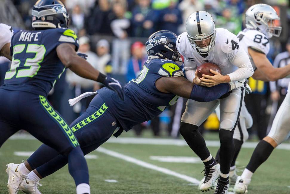 Raiders quarterback Derek Carr (4) is sacked by Seattle Seahawks defensive tackle Bryan Mone (9 ...