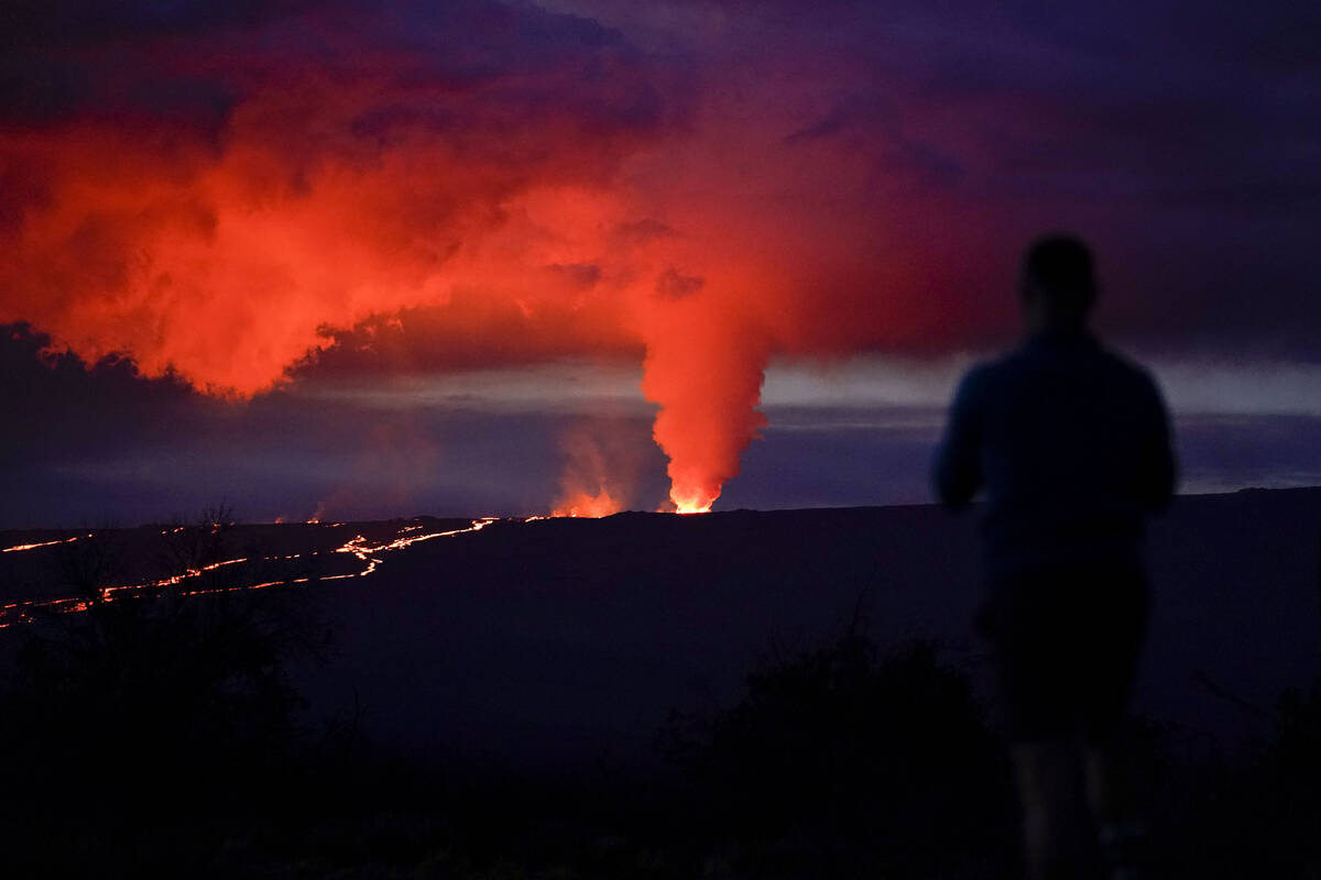 A man looks on as lava erupts from Hawaii's Mauna Loa volcano Wednesday, Nov. 30, 2022, near Hi ...