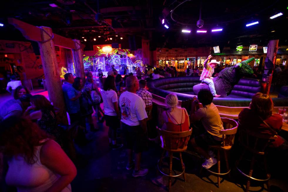 People watch a person ride a mechanical bull at Gilley's Saloon inside of Treasure Island hotel ...