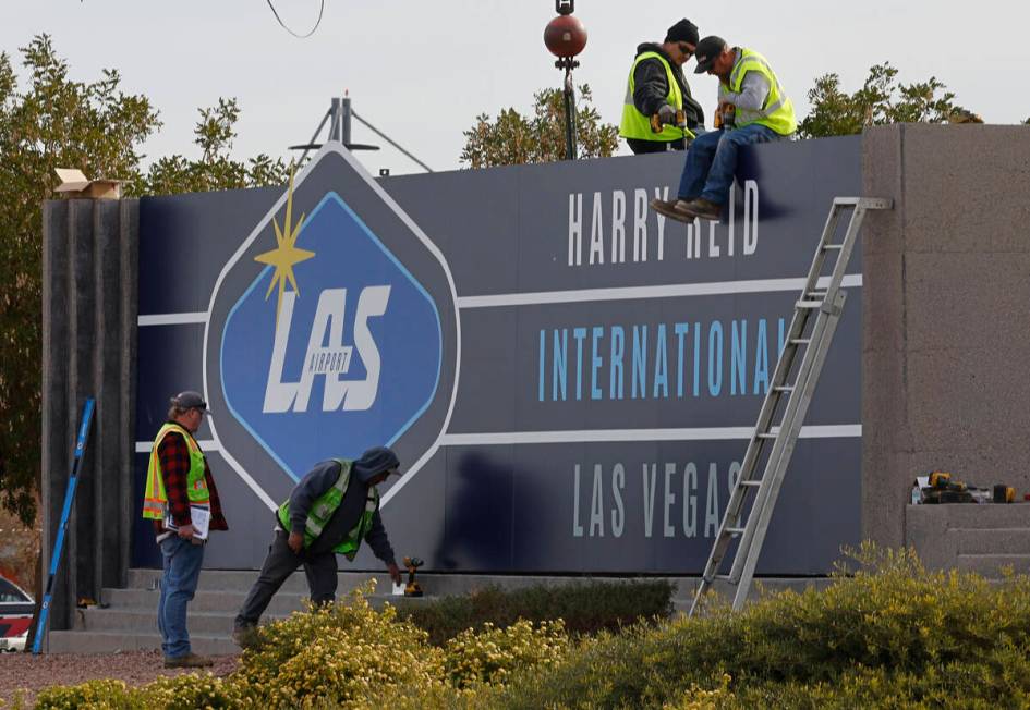Workers change signage from McCarran International Airport to Harry Reid at Koval Lane and Trop ...