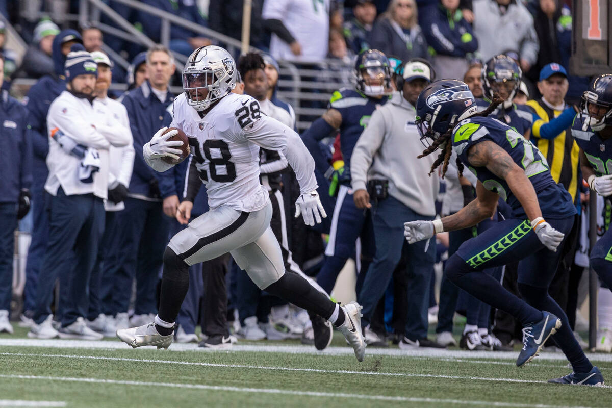 Raiders running back Josh Jacobs (28) runs past Seattle Seahawks safety Ryan Neal (26) to the e ...