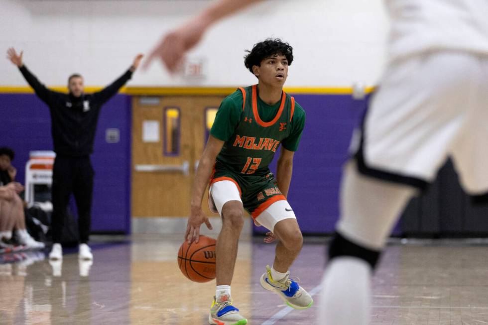 Mojave’s Nathan Sherrard (13) dribbles before passing during a boys high school basketba ...