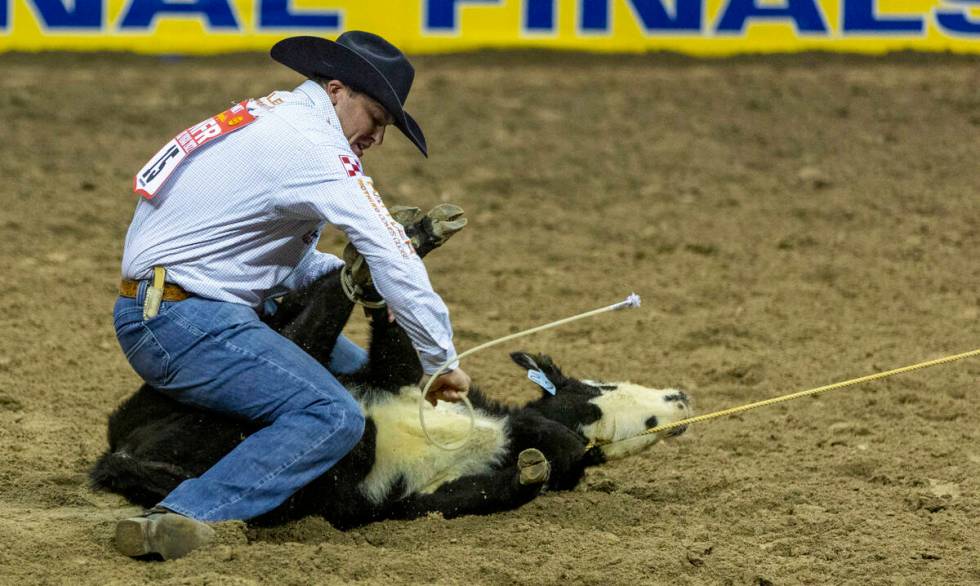 Caleb Smidt of Bellville, Texas, secures his calf while on a winning time in Tie-Down Roping du ...