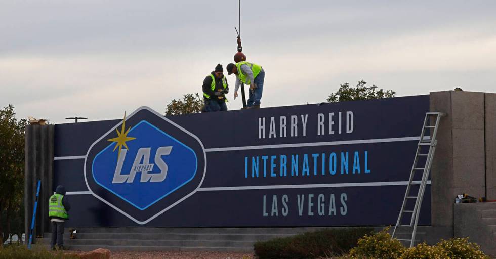 Workers change signage from McCarran International Airport to Harry Reid at Koval Lane and Trop ...