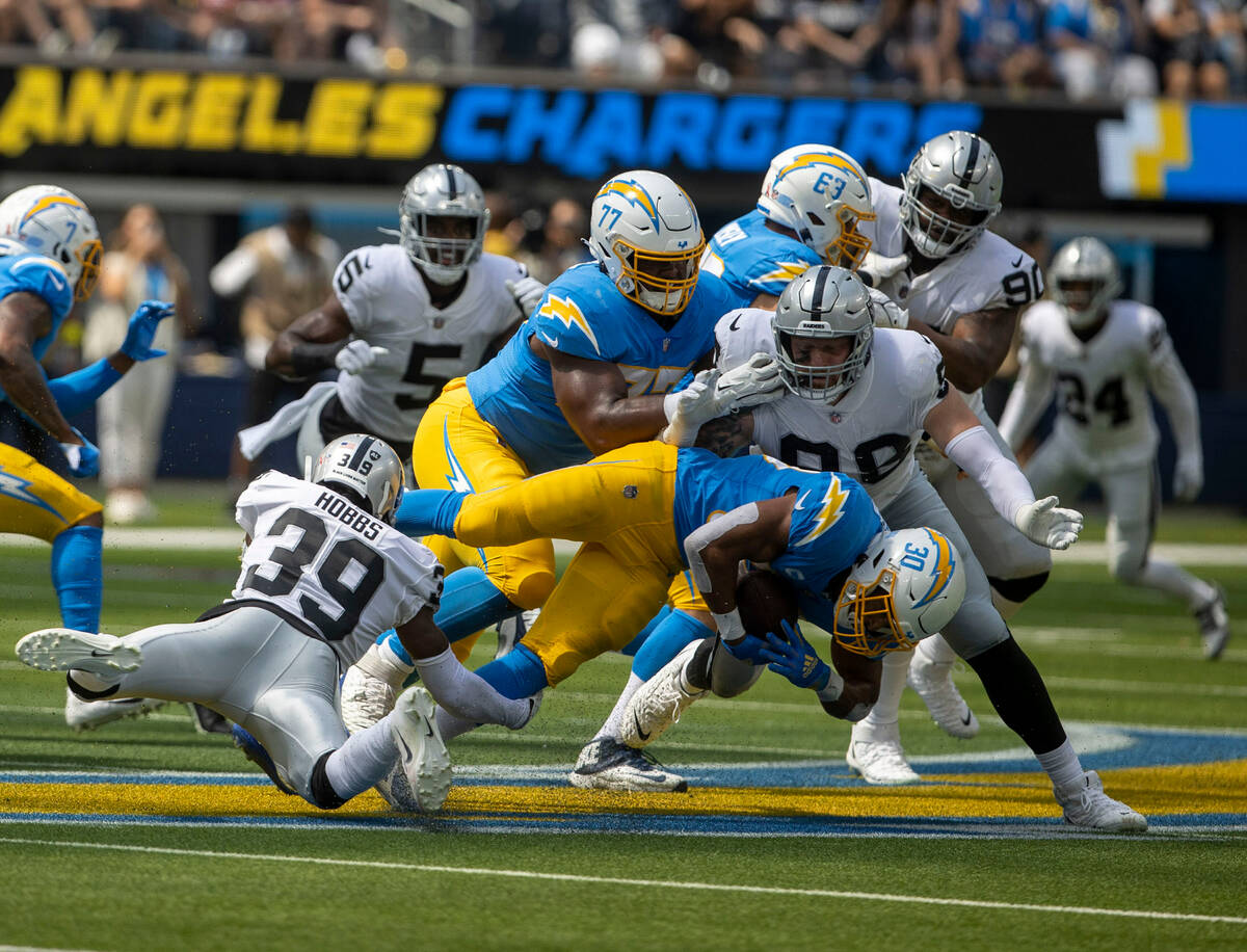 Raiders cornerback Nate Hobbs (39) and defensive end Maxx Crosby (98) tackle Los Angeles Charge ...