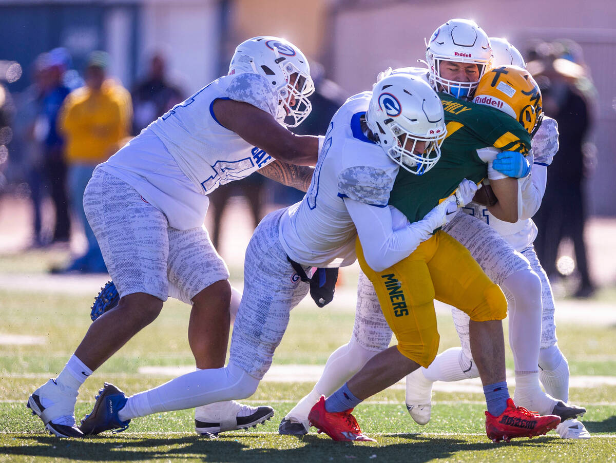 (From left) Bishop Gorman DL Aiden McComber (44), DE John Corrigan (19) and others drive back B ...