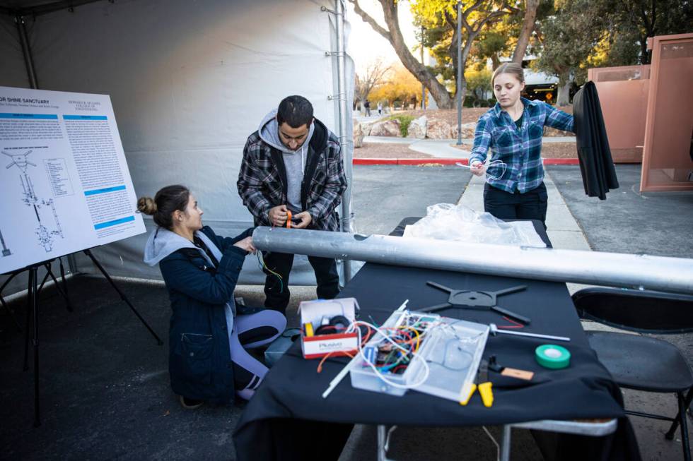 UNLV students, from left, Denisse Franco, Tayler Zolyniak, and Ramy Georgi set up their Rain or ...