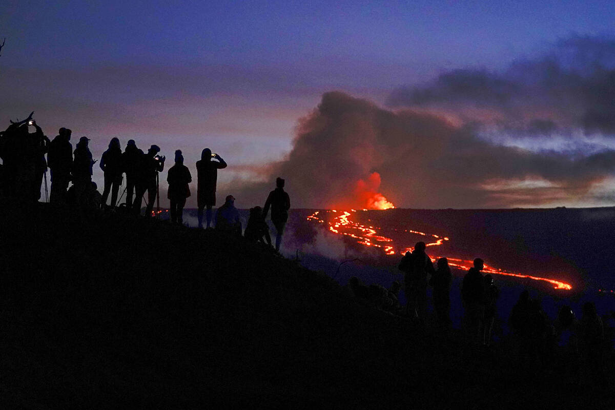 FILE - People watch and record images of lava from the Mauna Loa volcano Thursday, Dec. 1, 2022 ...