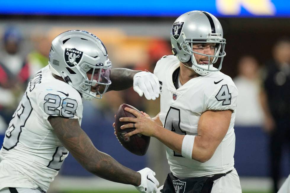 Las Vegas Raiders quarterback Derek Carr drops back as running back Josh Jacobs gets ready for ...