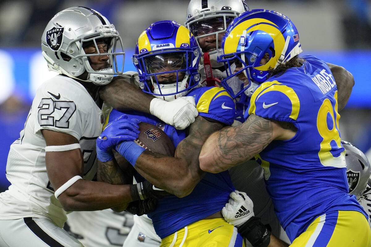 Los Angeles Rams running back Cam Akers, center, is brought down by Las Vegas Raiders cornerbac ...