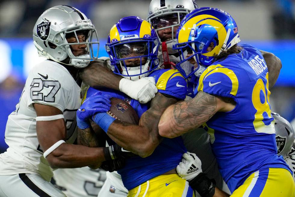 Los Angeles Rams running back Cam Akers, center, is brought down by Las Vegas Raiders cornerbac ...