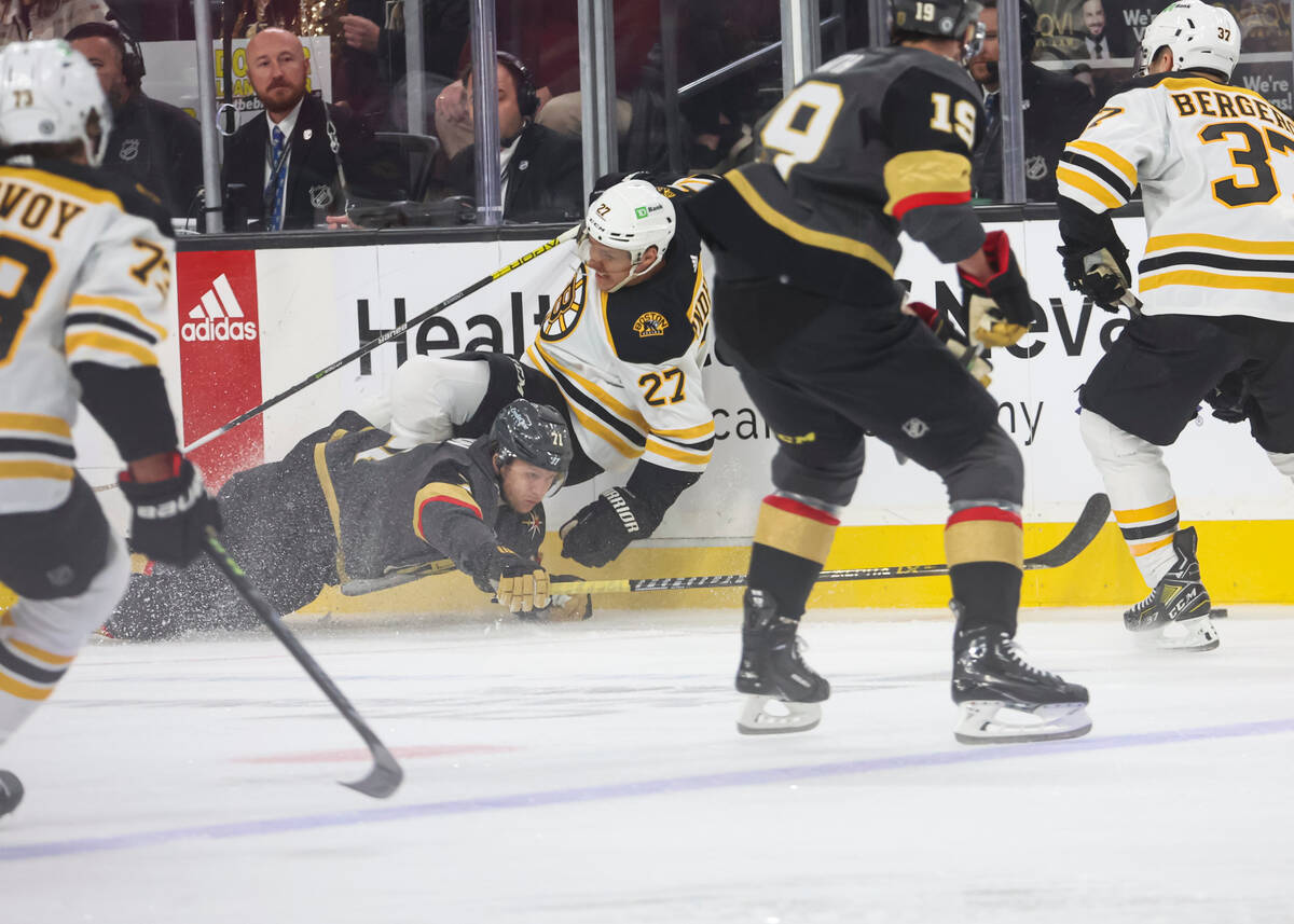 Golden Knights center William Karlsson (71) gets tripped up by Boston Bruins defenseman Hampus ...