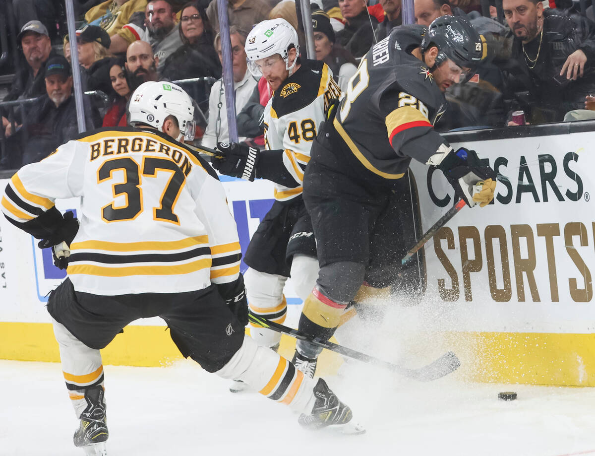 Golden Knights left wing William Carrier (28) gets tangled up with Boston Bruins defenseman Mat ...