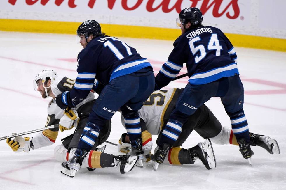 Winnipeg Jets' Adam Lowry (17) and Dylan Samberg (54) check Vegas Golden Knights' Nicolas Roy ( ...