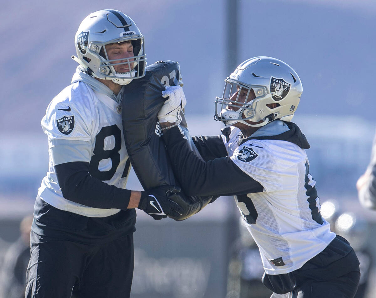 Raiders tight end Foster Moreau (87), left, holds pads as tight end Darren Waller (83) drills d ...