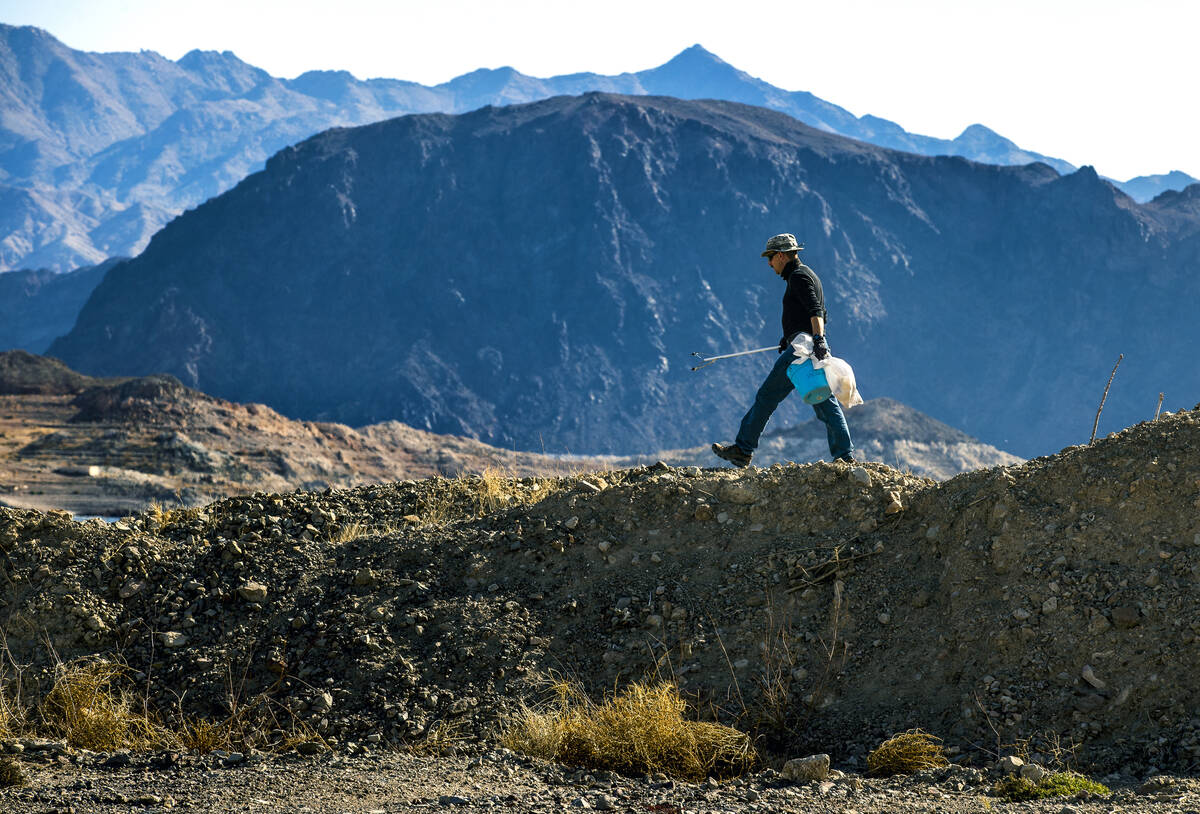 Volunteer Kevin Long of Henderson with Get Outdoors Nevada eyes a rock berm for trash as his or ...