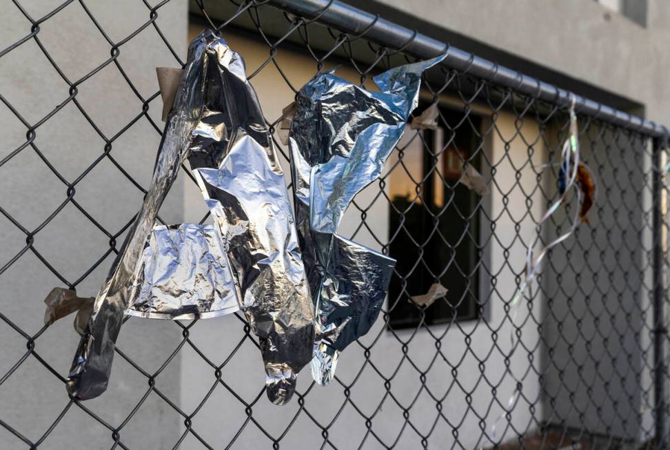 Morning light begins to illuminate deflated balloons on the fence surrounding the former Alpine ...