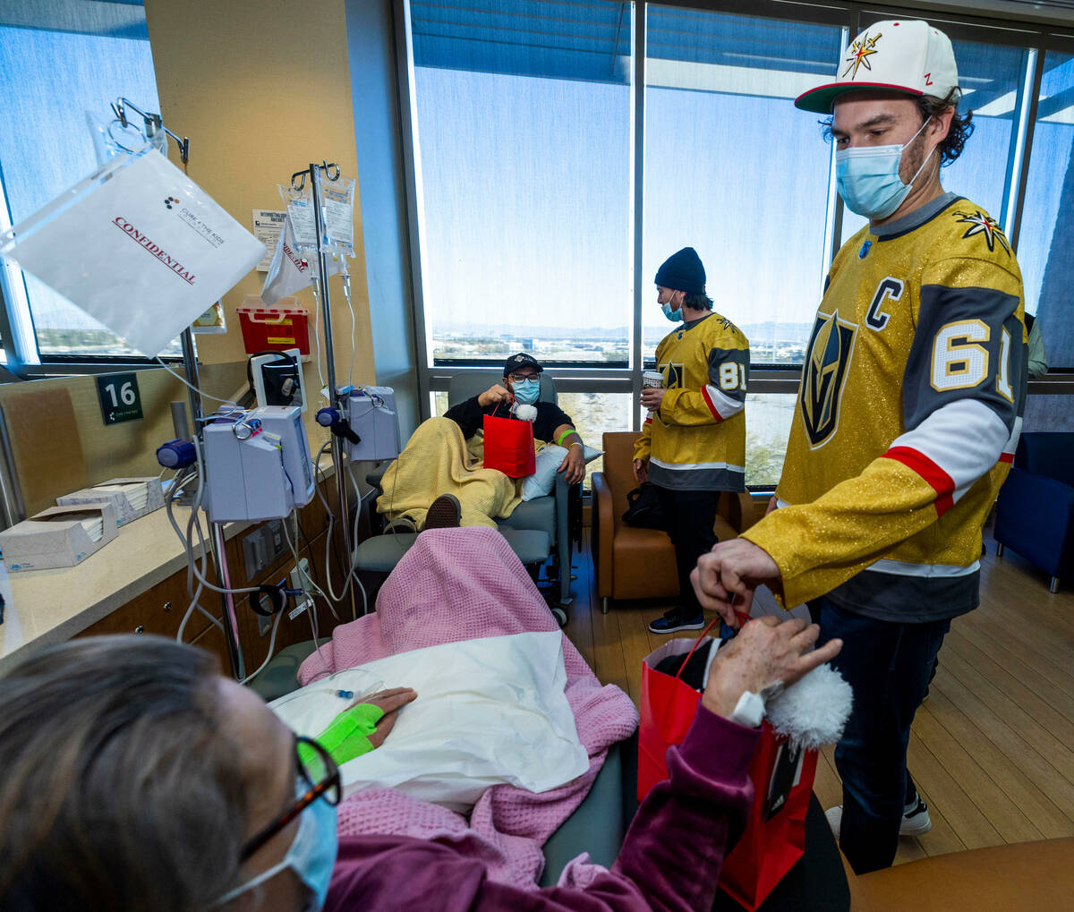 A patient receives a gift bag from Mark Stone (61) as Jonathan Marchessault (81) gives another ...